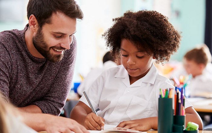 Male teacher teaching a student in uniform