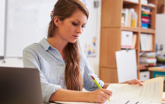 young teacher writing reports at desk